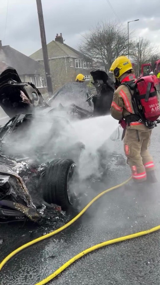 Firefighters extinguishing a burning car.