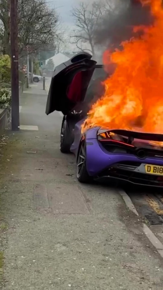 A purple McLaren engulfed in flames on a residential street.