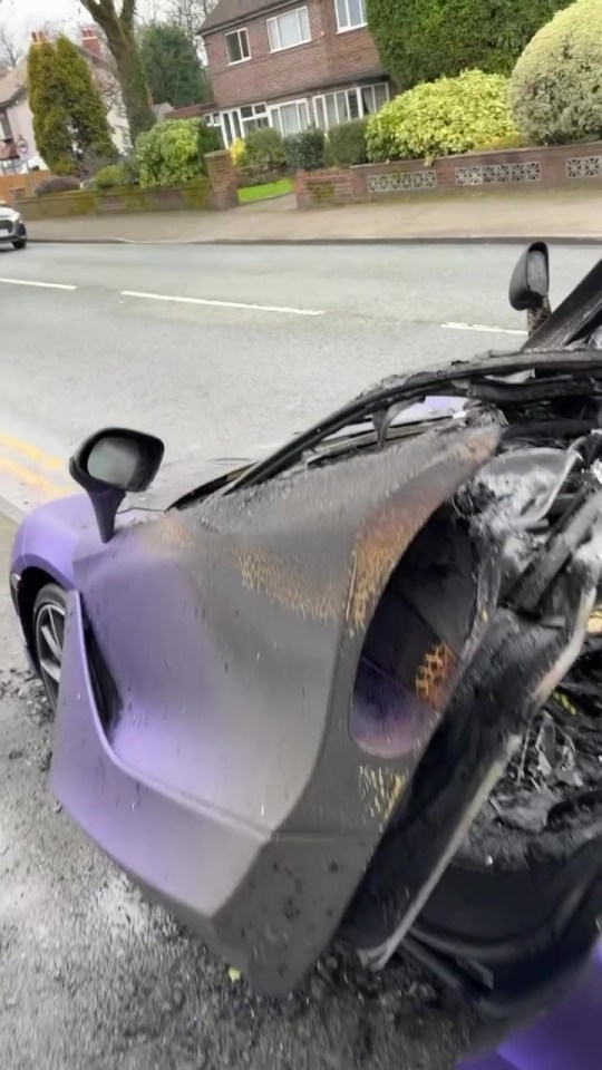 Burned-out purple car on a residential street.