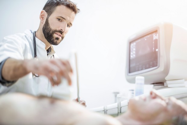 Healthcare worker performing an ultrasound on a patient.