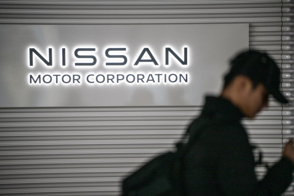 Person walking past a Nissan Motor Corporation sign.