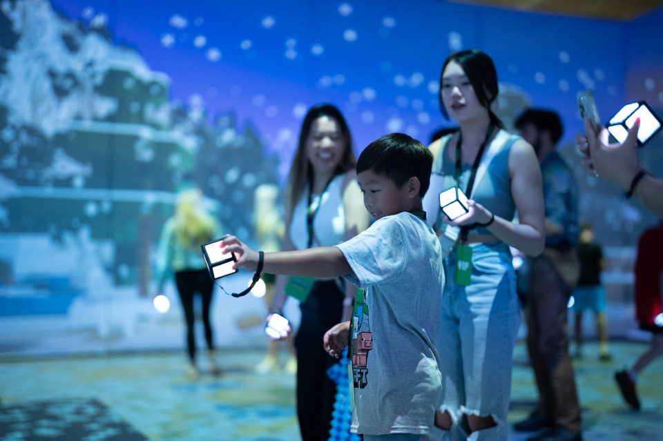 People interacting with illuminated cubes at a Minecraft attraction.