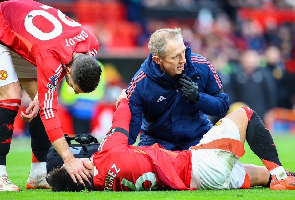 Lisandro Martinez injured on the field, receiving medical attention.