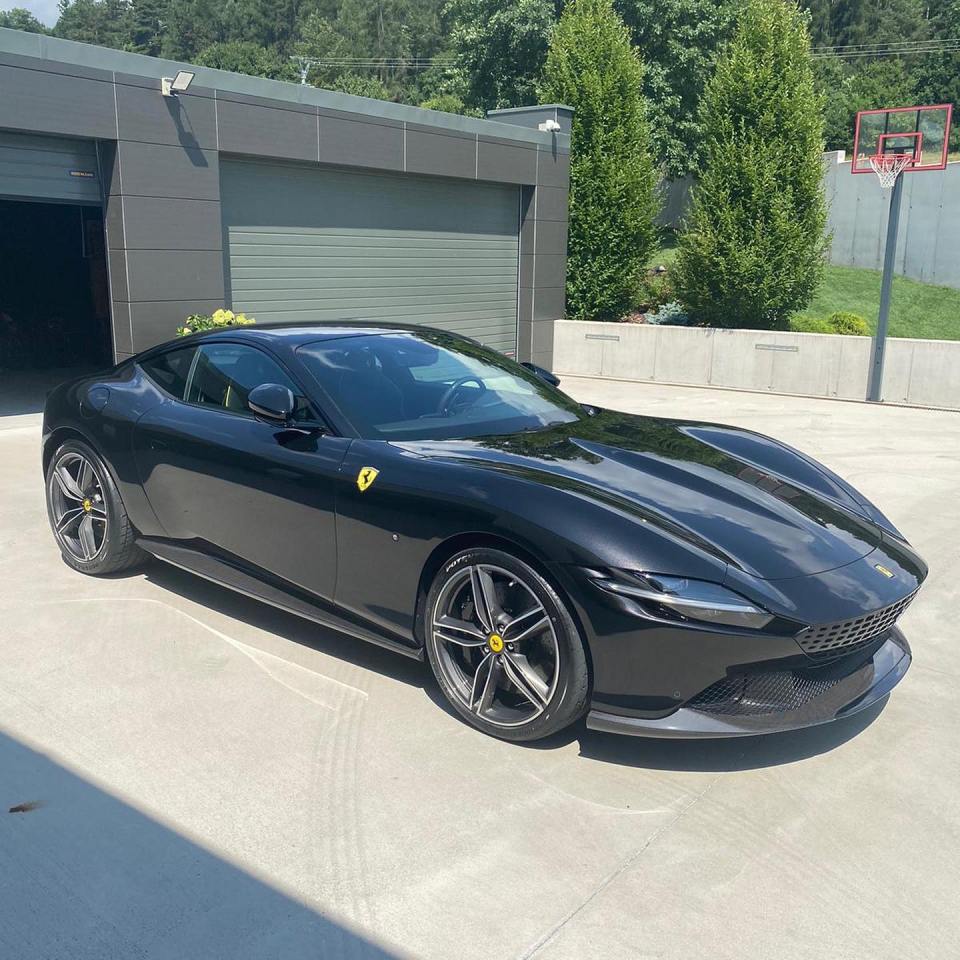 Black Ferrari parked in front of a garage.