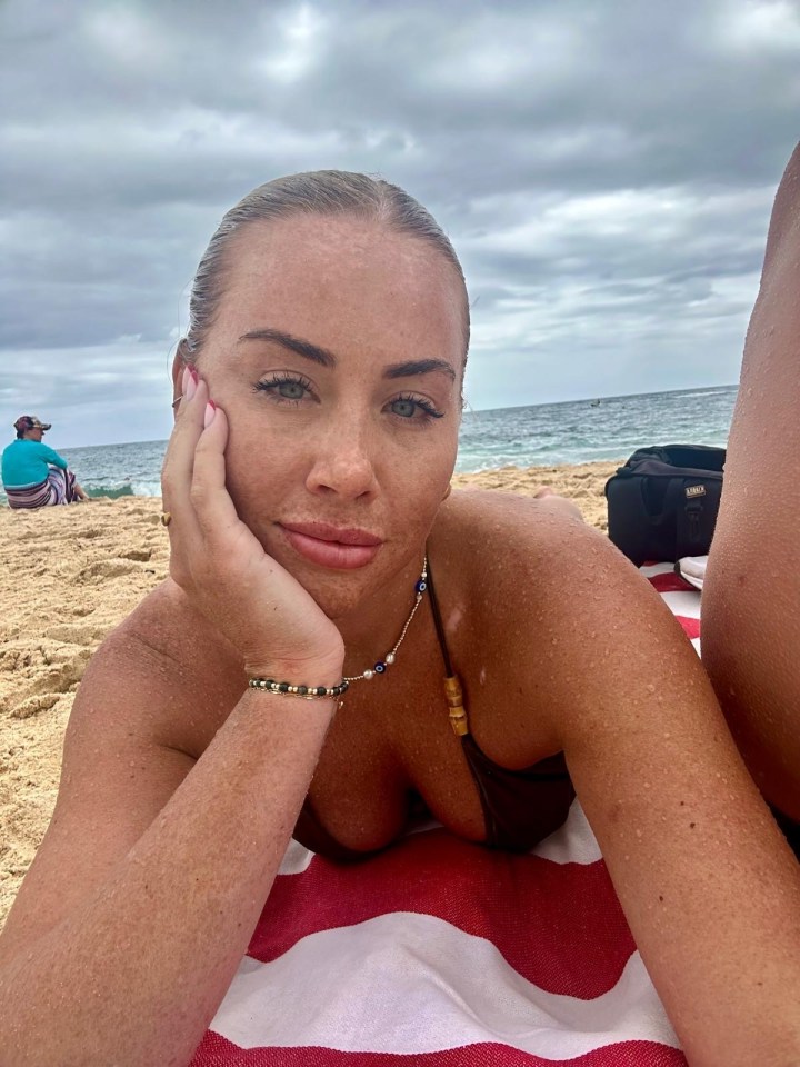 Polly Sellman lying on a beach towel on the sand.