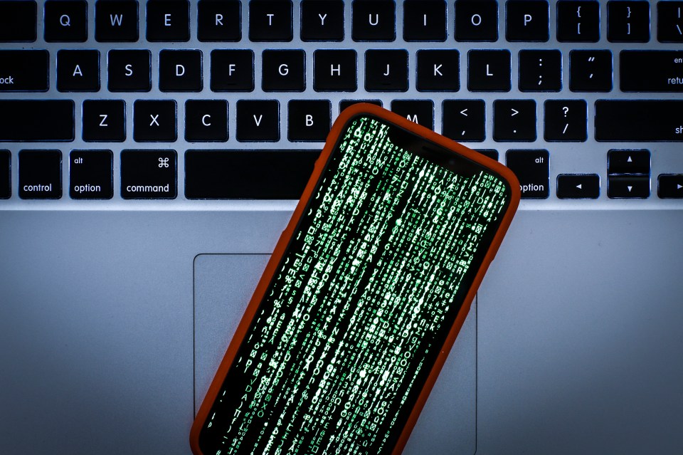 iPhone displaying Matrix-style code on laptop keyboard.