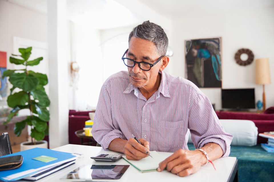 Man wearing glasses working on his finances at home.