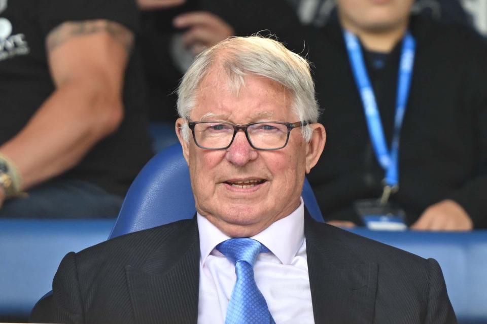 Sir Alex Ferguson seated at a sporting event.