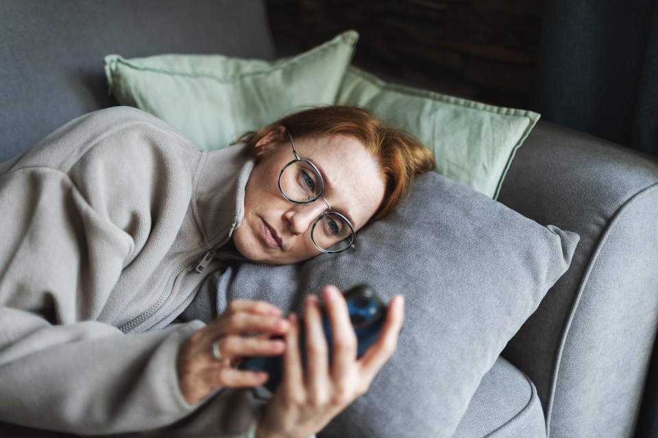 Woman lying on a couch looking at her phone.