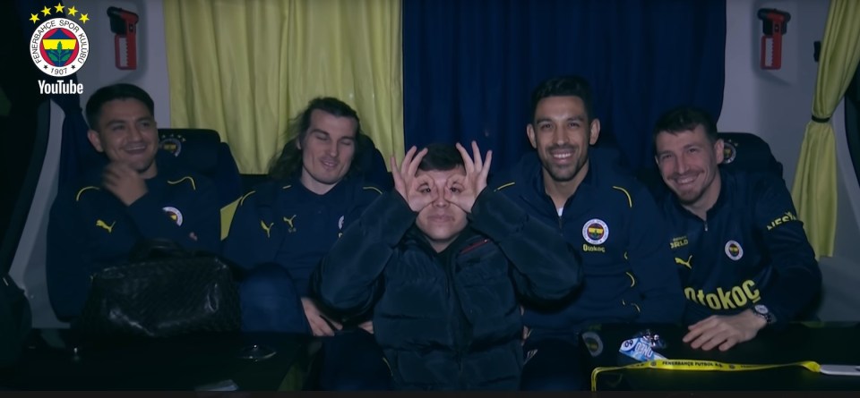 Fenerbahce soccer players with a fan on their team bus.