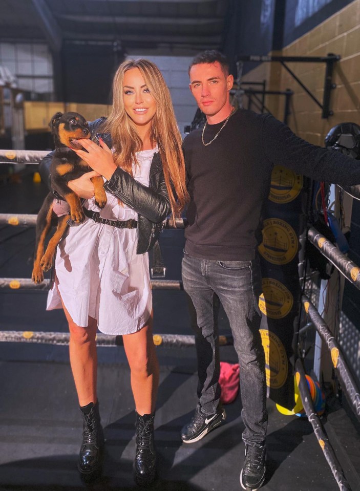 A couple holding a Rottweiler puppy in a boxing gym.