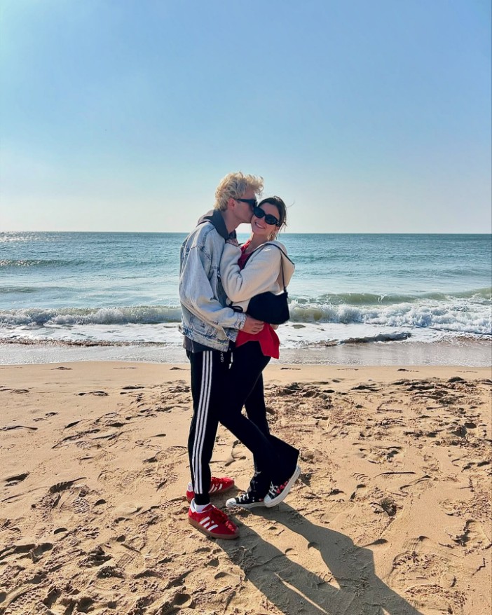 Tristan Evans and Nikki Banner embracing on a beach.