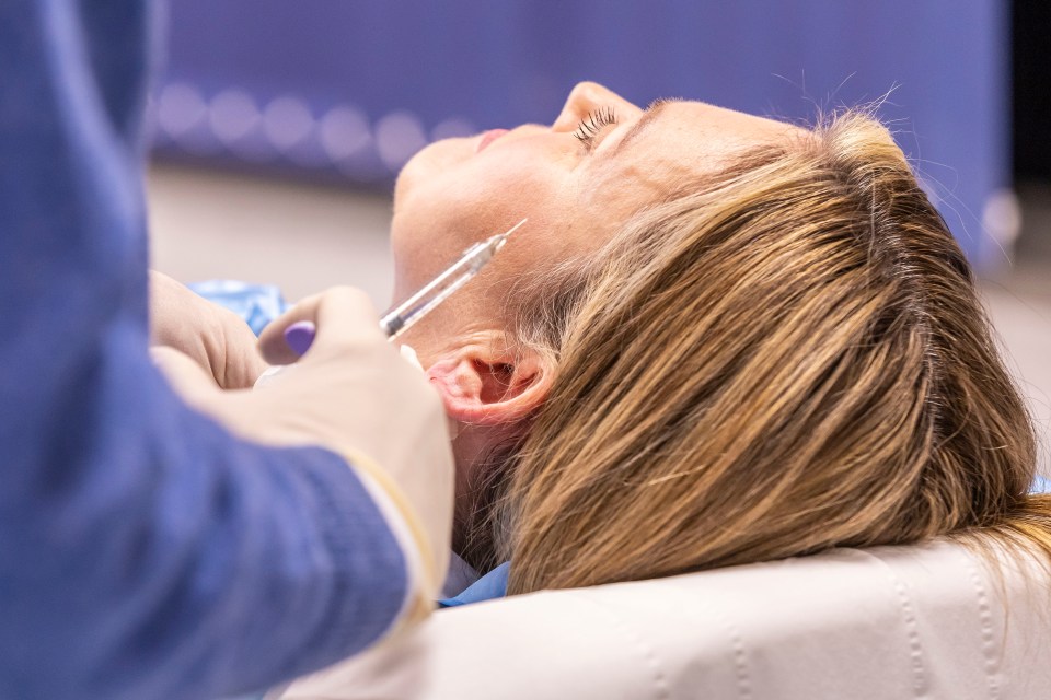 Close-up of a woman receiving an earlobe filler injection.