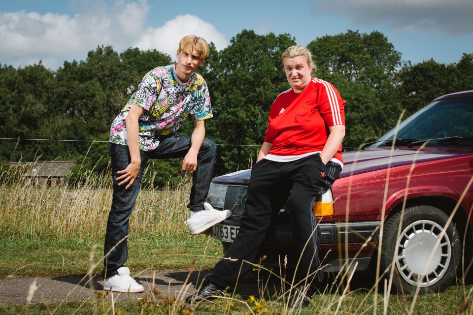 Two people leaning on a car.