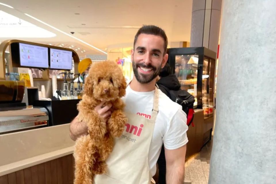 Man holding a small brown dog in a cafe.