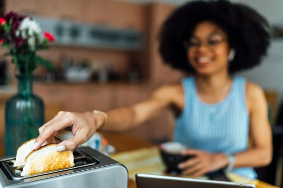 Woman putting bread into a toaster.