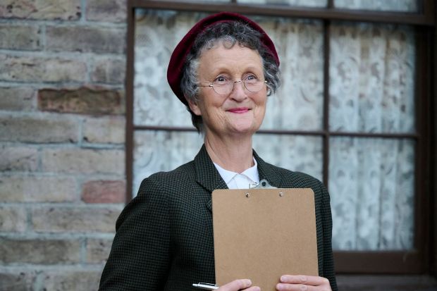 Smiling woman in glasses holding a clipboard.