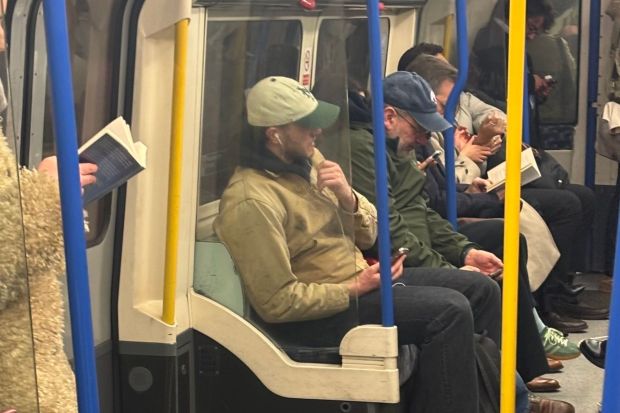 Passengers reading and using phones on a subway car.