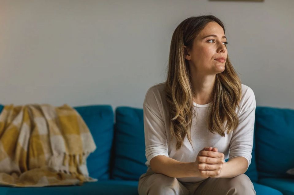 Woman sitting on a couch, looking thoughtful.