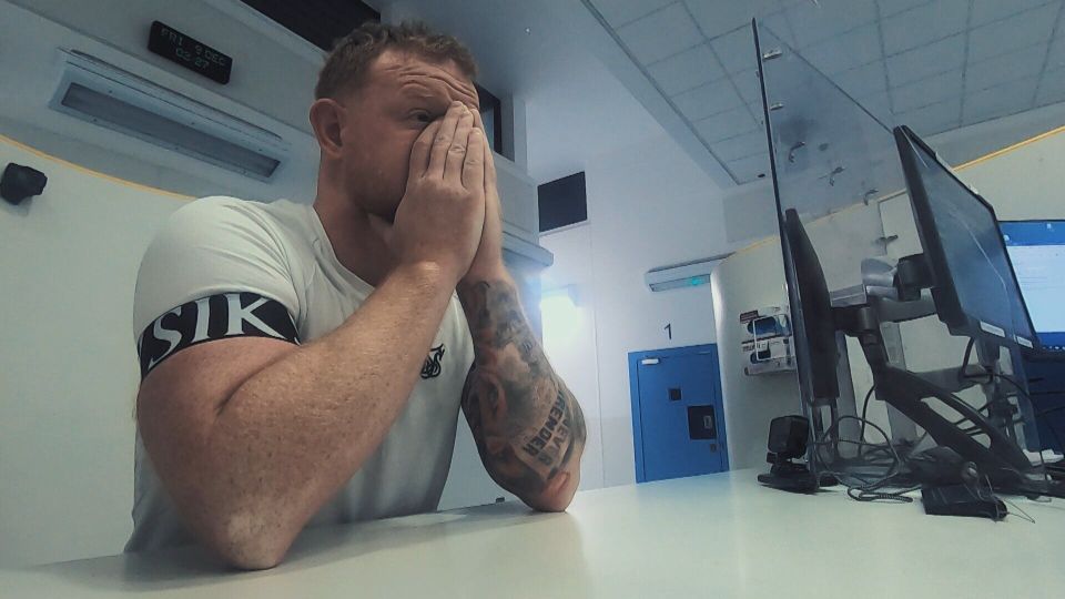 Man with hands covering his face sitting at a desk.