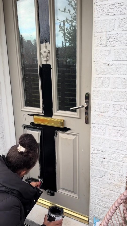 Person painting a door black.