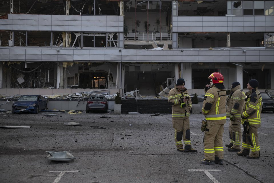 Firefighters assess damage to a building after a missile strike.