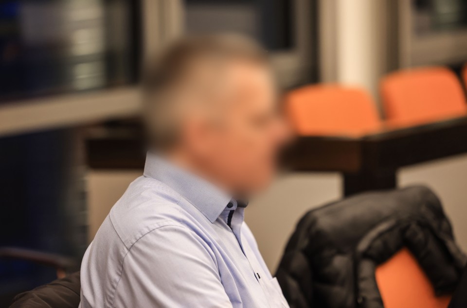 Blurred photo of a defendant in a courtroom.