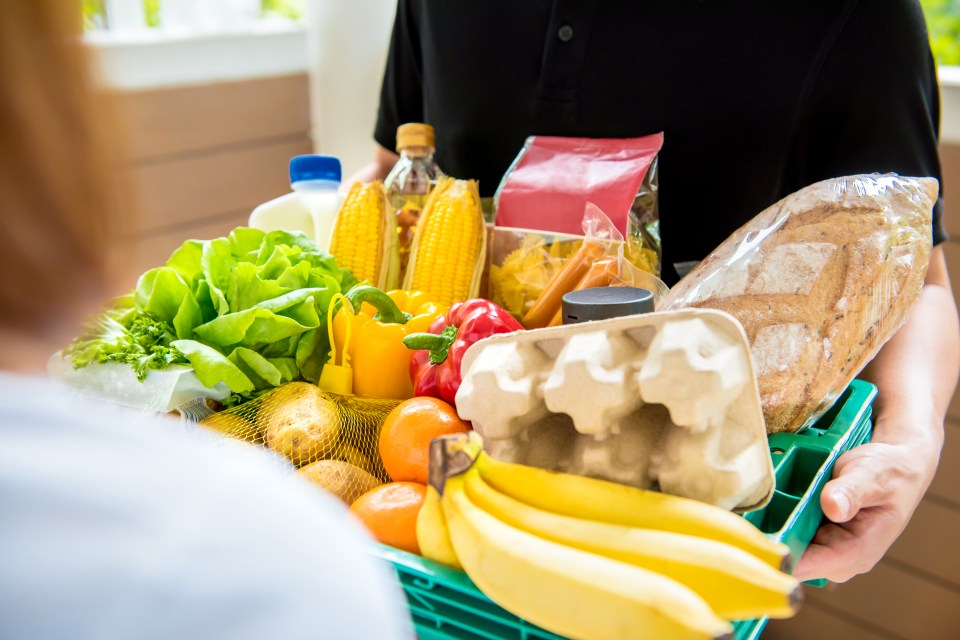 Delivery person handing a customer a crate of groceries.