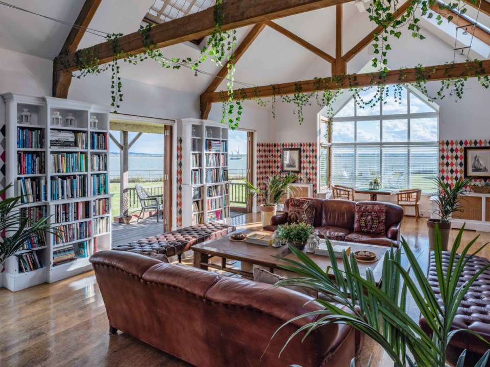 Interior of a room with leather sofas, bookshelves, and a view of the water.