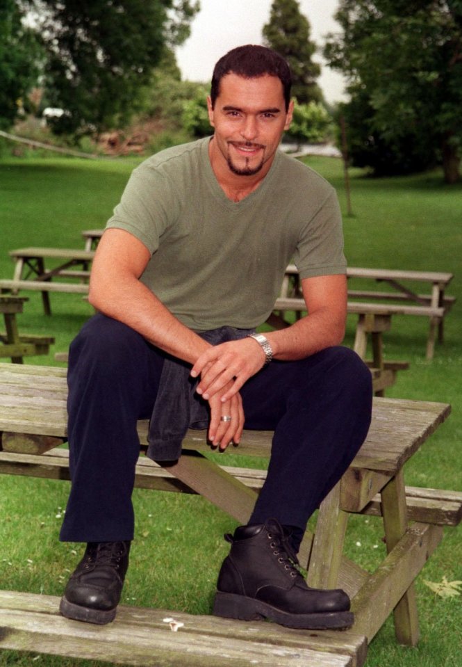 Michael Greco, EastEnders actor, sitting on a park bench.