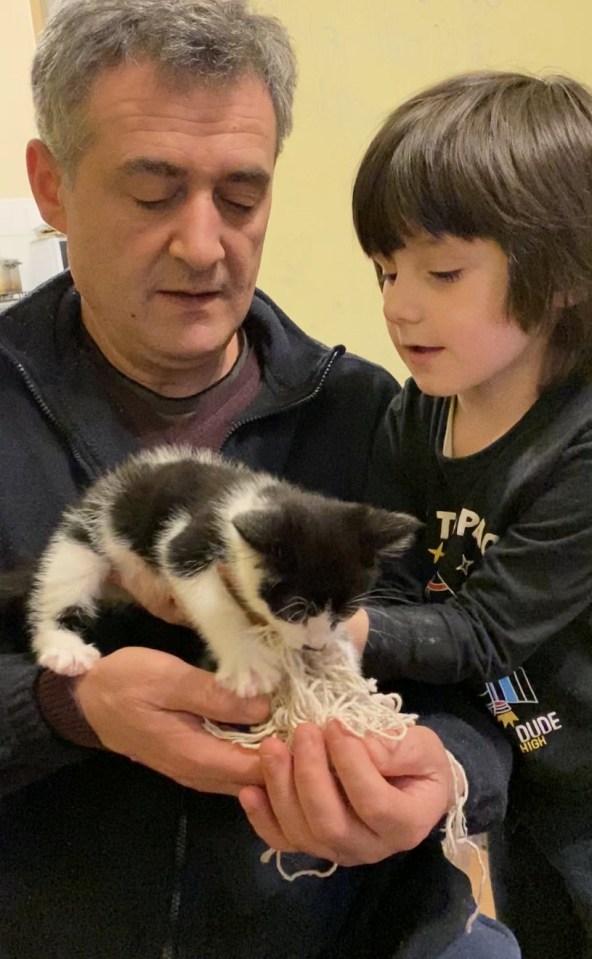 A man and child holding a black and white kitten.