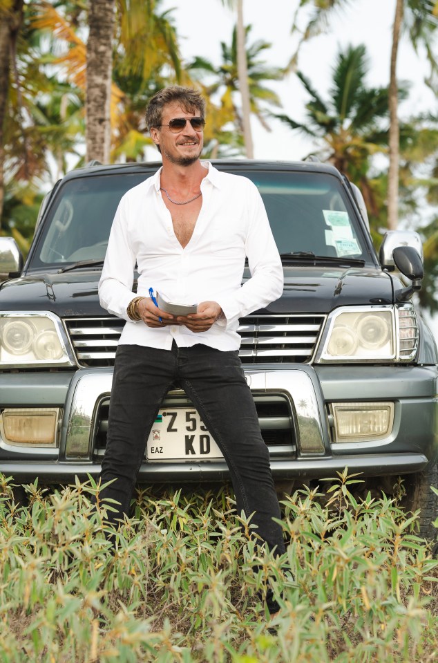 Man in white shirt standing in front of SUV, taking notes.