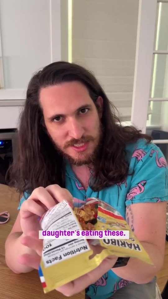 Man showing a bag of Haribo gummy bears his daughter is eating.