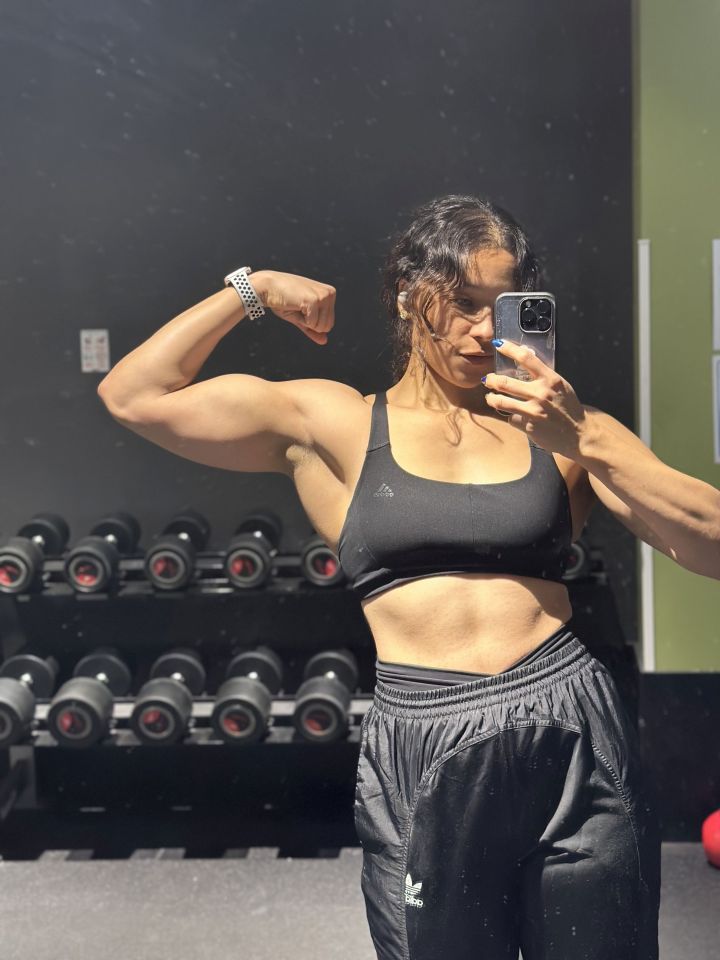 Personal trainer flexing her biceps in a gym.