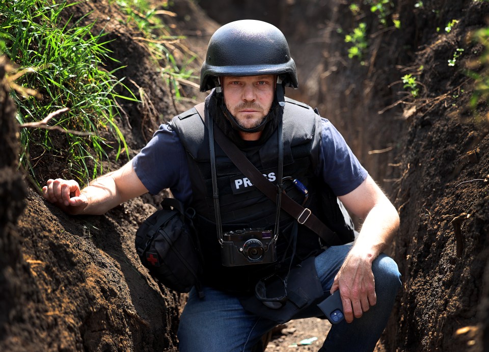 A journalist in a helmet and protective vest in a trench near Bakhmut.