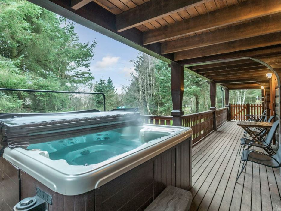 Hot tub on a wooden deck overlooking a forest.