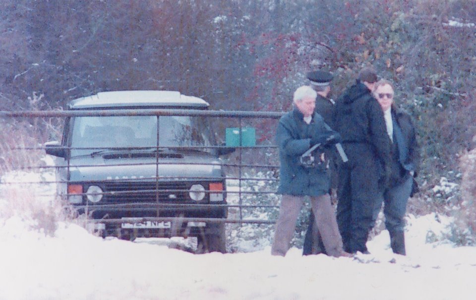 Police officers examining a Range Rover in the snow.