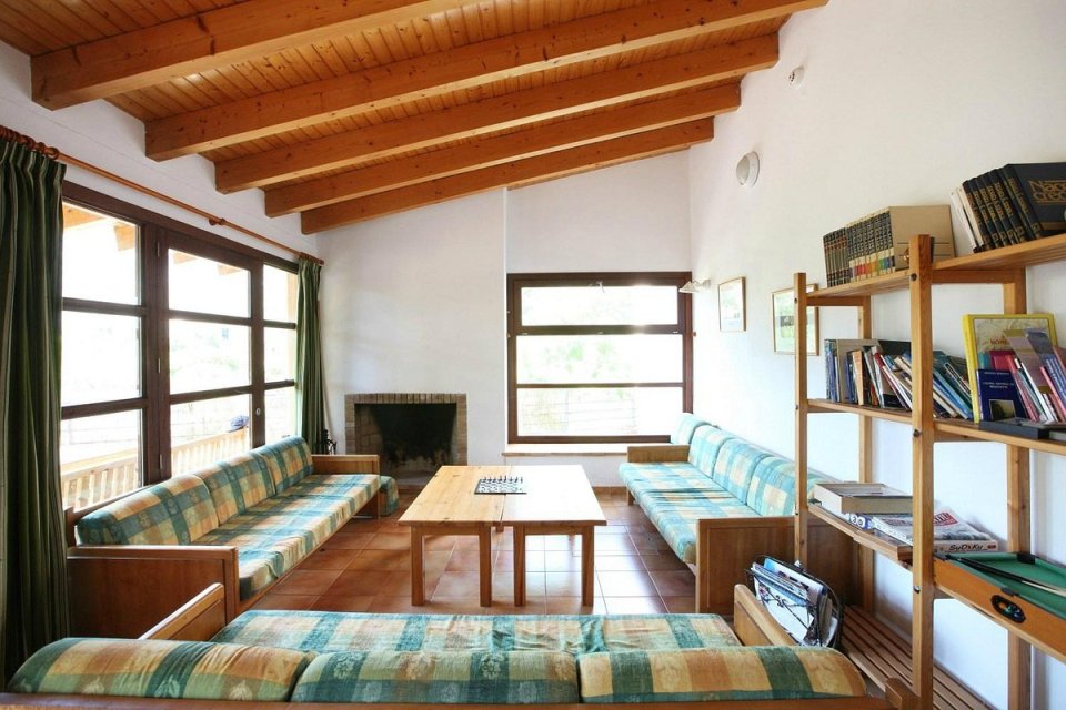 Lounge area with wooden couches, a wooden coffee table, a fireplace, and a bookshelf.