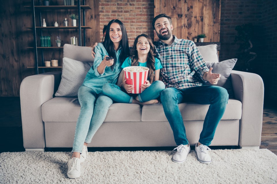 Happy family watching TV together on a couch.