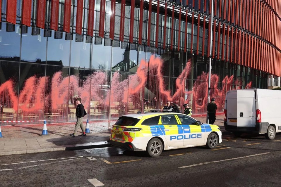 Red paint splattered on a university building; police on the scene.