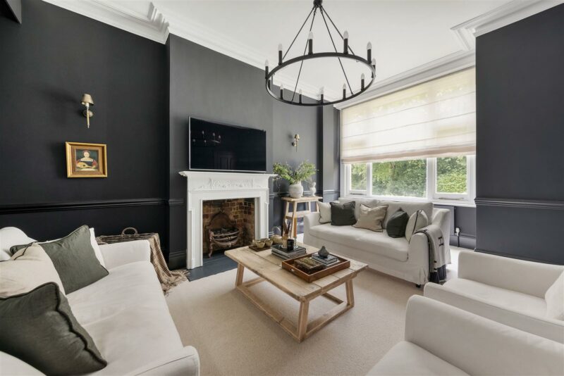 Living room with dark walls, white sofas, and a large chandelier.