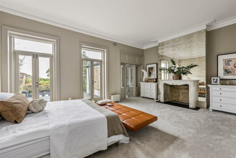 Master bedroom with large bed, fireplace, and French doors leading to a patio.