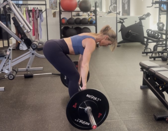 Woman performing a deadlift in a gym.