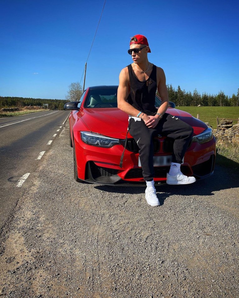 Man sitting on the hood of a red car.