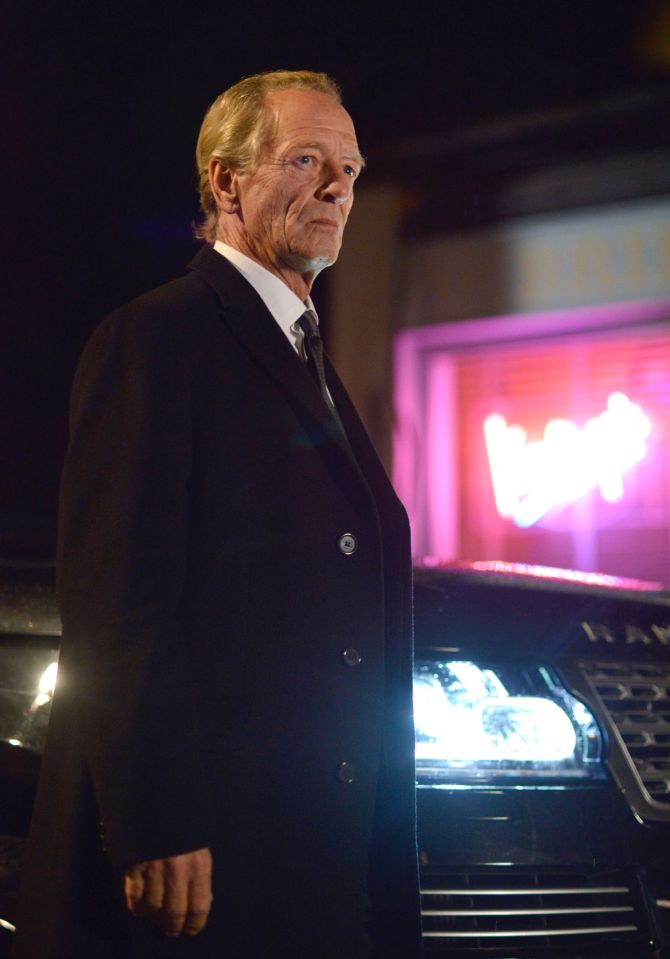 James Willmott-Brown, EastEnders villain, standing by a car at night.