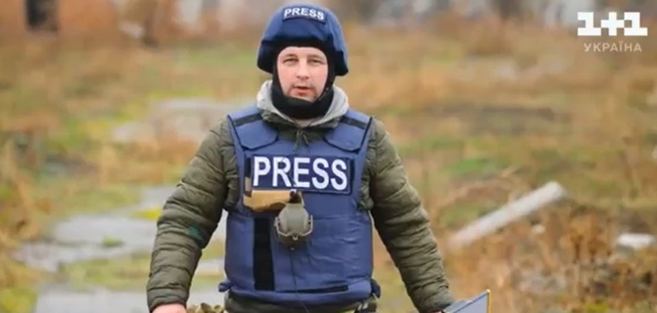 Ukrainian cameraman, wearing a helmet and bulletproof vest marked "PRESS," during wartime.