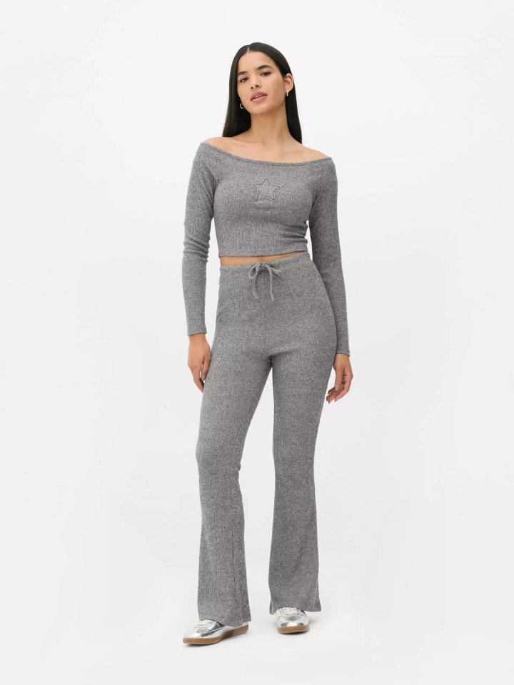 Woman modeling a gray ribbed knit off-the-shoulder top and flare pants.