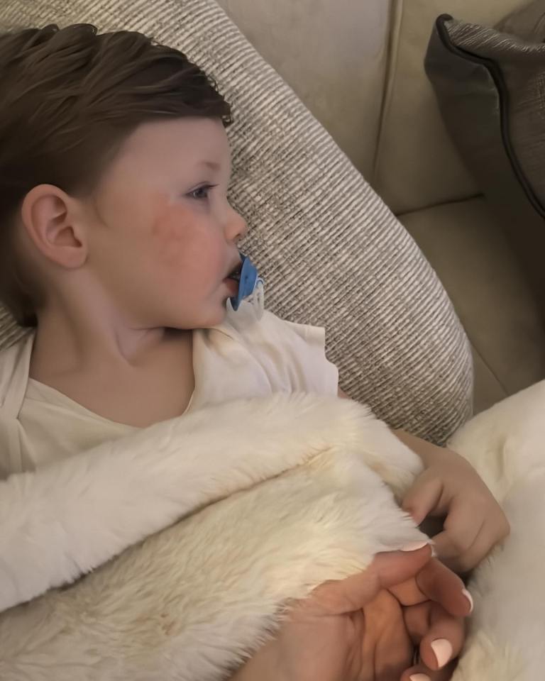 Sick toddler lying in bed with a pacifier.