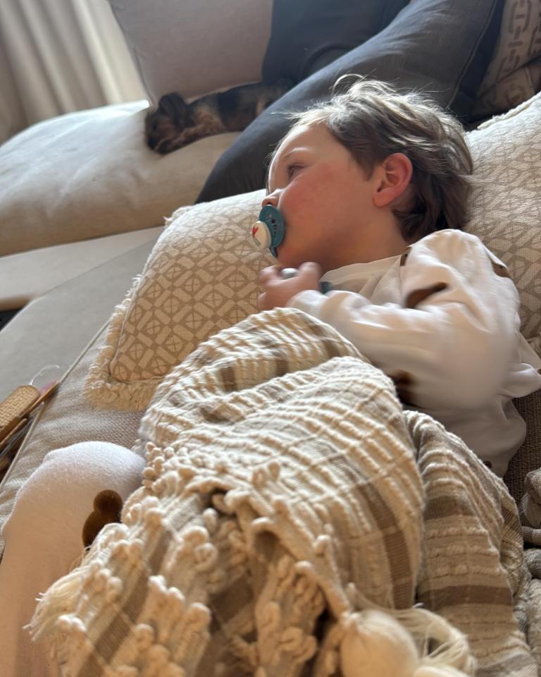 Sick toddler lying on a couch with a pacifier.