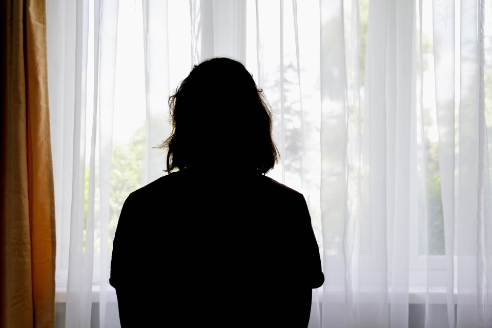 Silhouette of a woman sitting by a window.